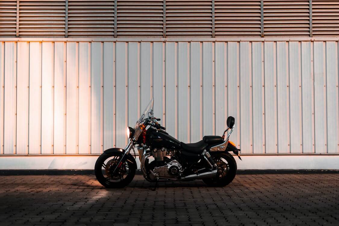 a beautiful black chromed motorcycle in front of a white wall