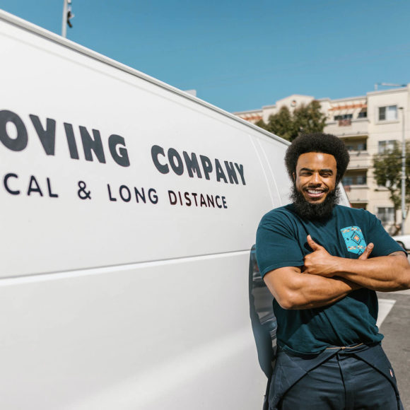 a mover smiling and standing in front of a relocation van