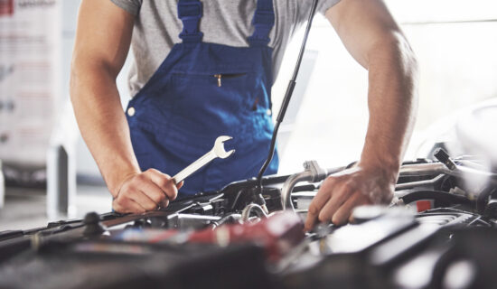 A man in blue overalls fixing a car