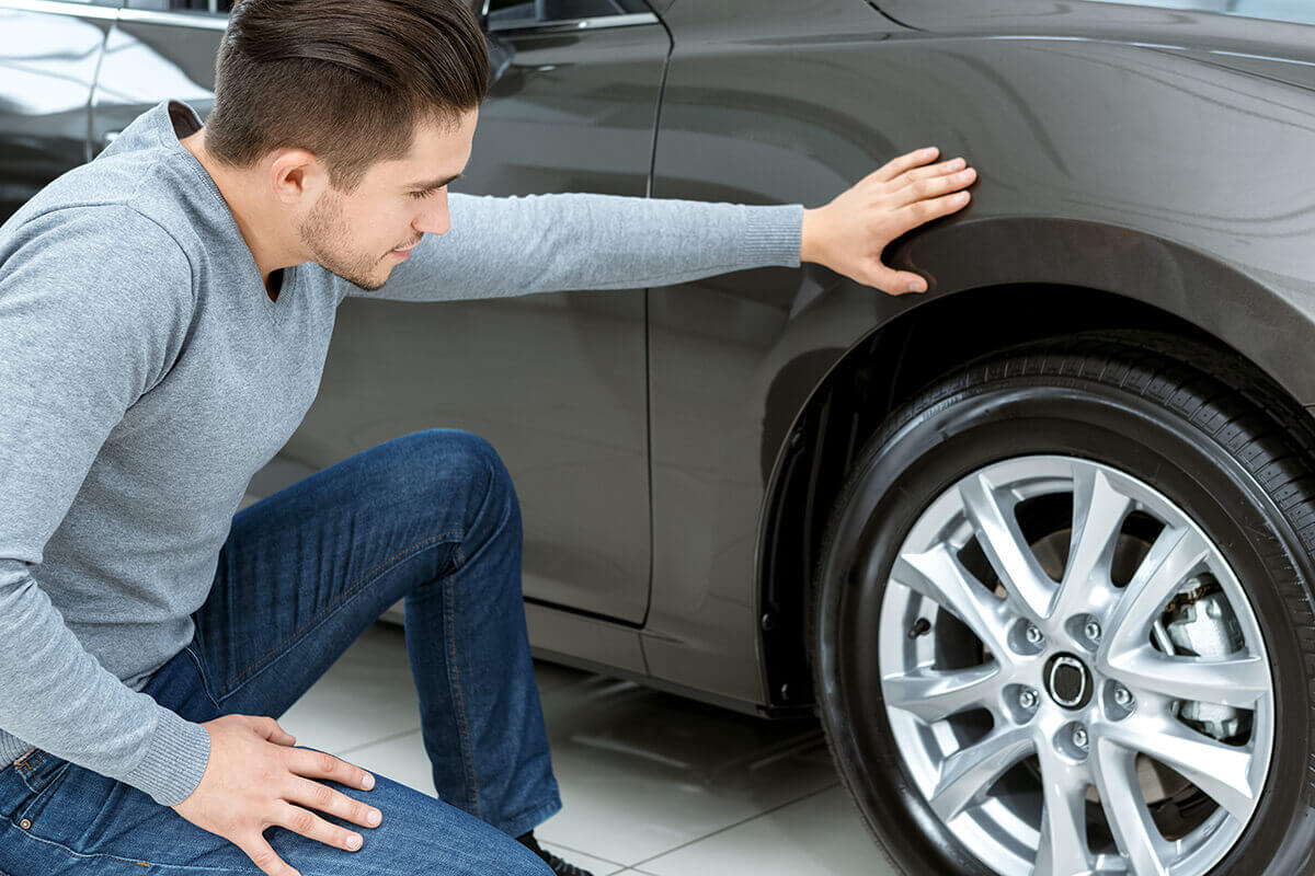 A man next to his car checking the tire