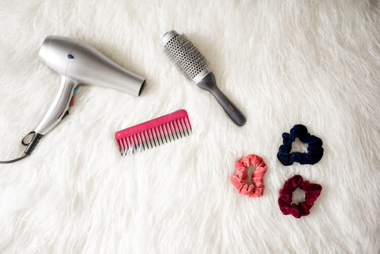 Gray corded hair dryer and comb on the bed
