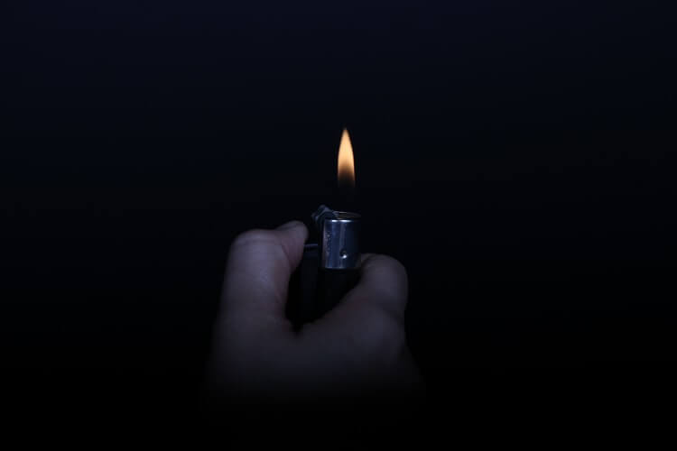 A person holding a lighted lighter