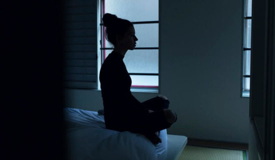 Young woman sitting on her bed looking depressed