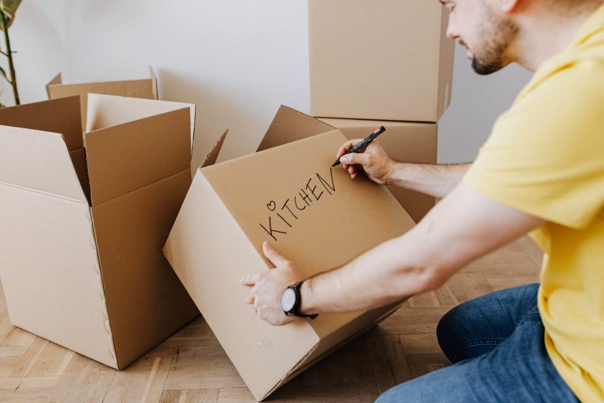 A man labeling a box before a long-distance moving