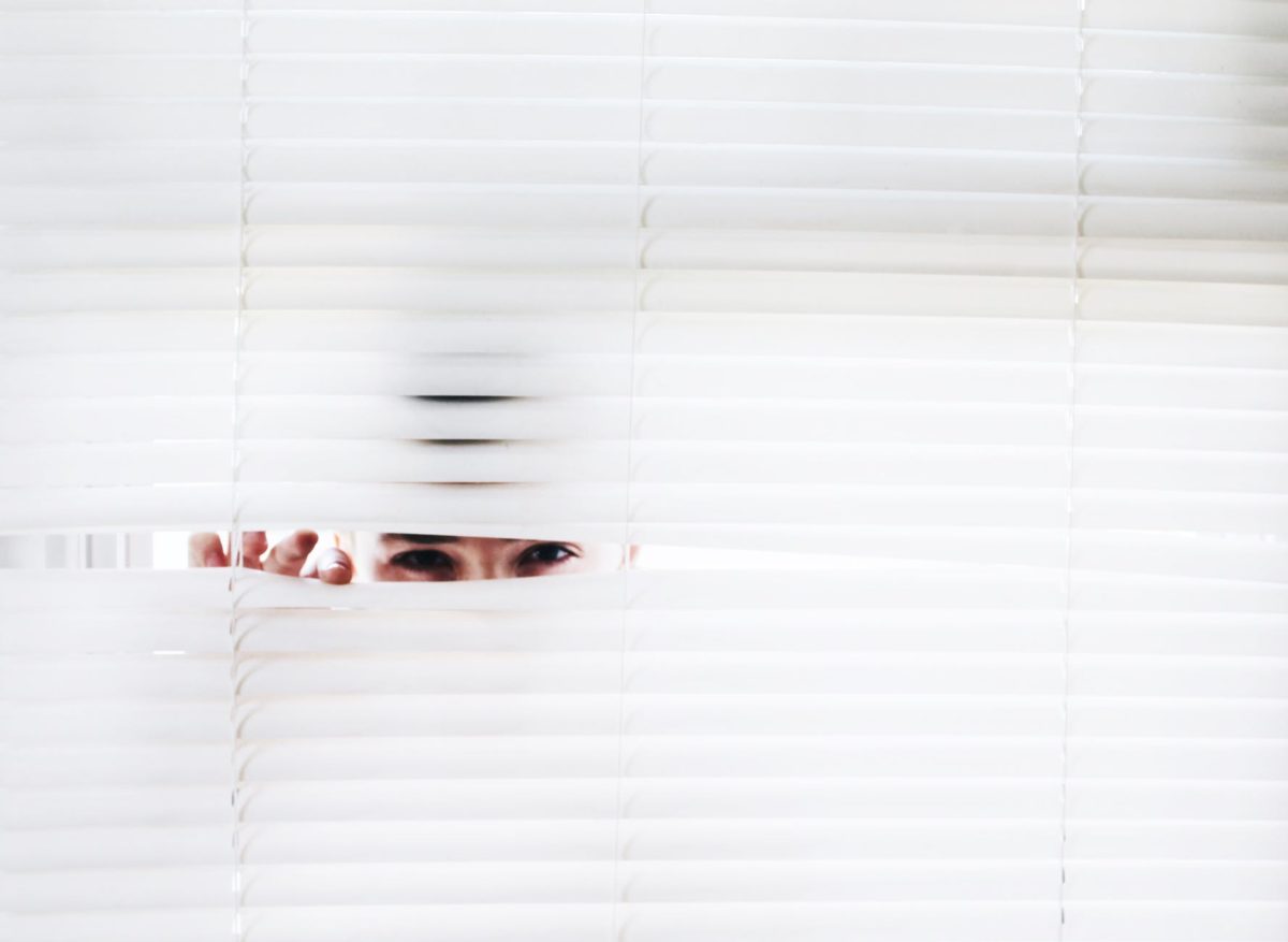 Woman peeking through a blinds