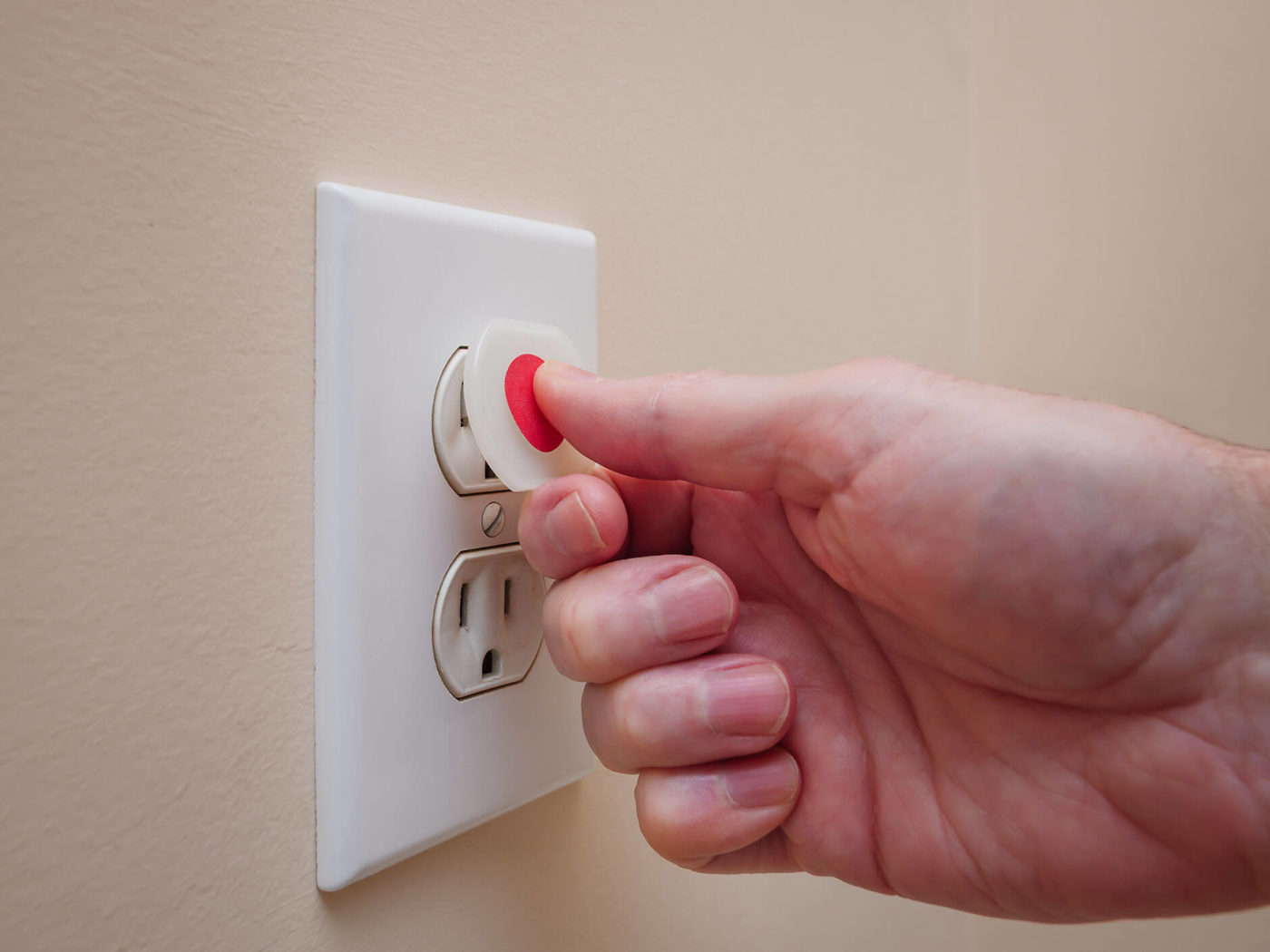 A hand taping over an electrical outlet