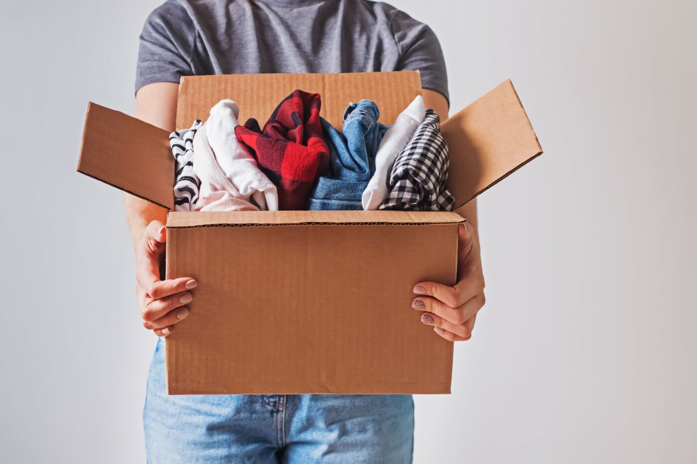 Person holding a box packed with clothing