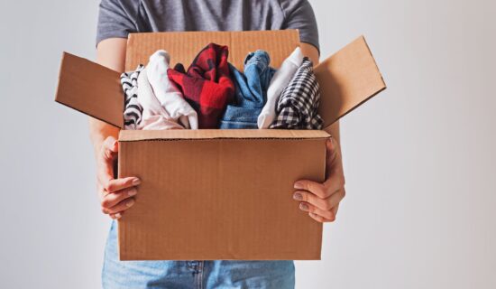 Person holding a box packed with clothing