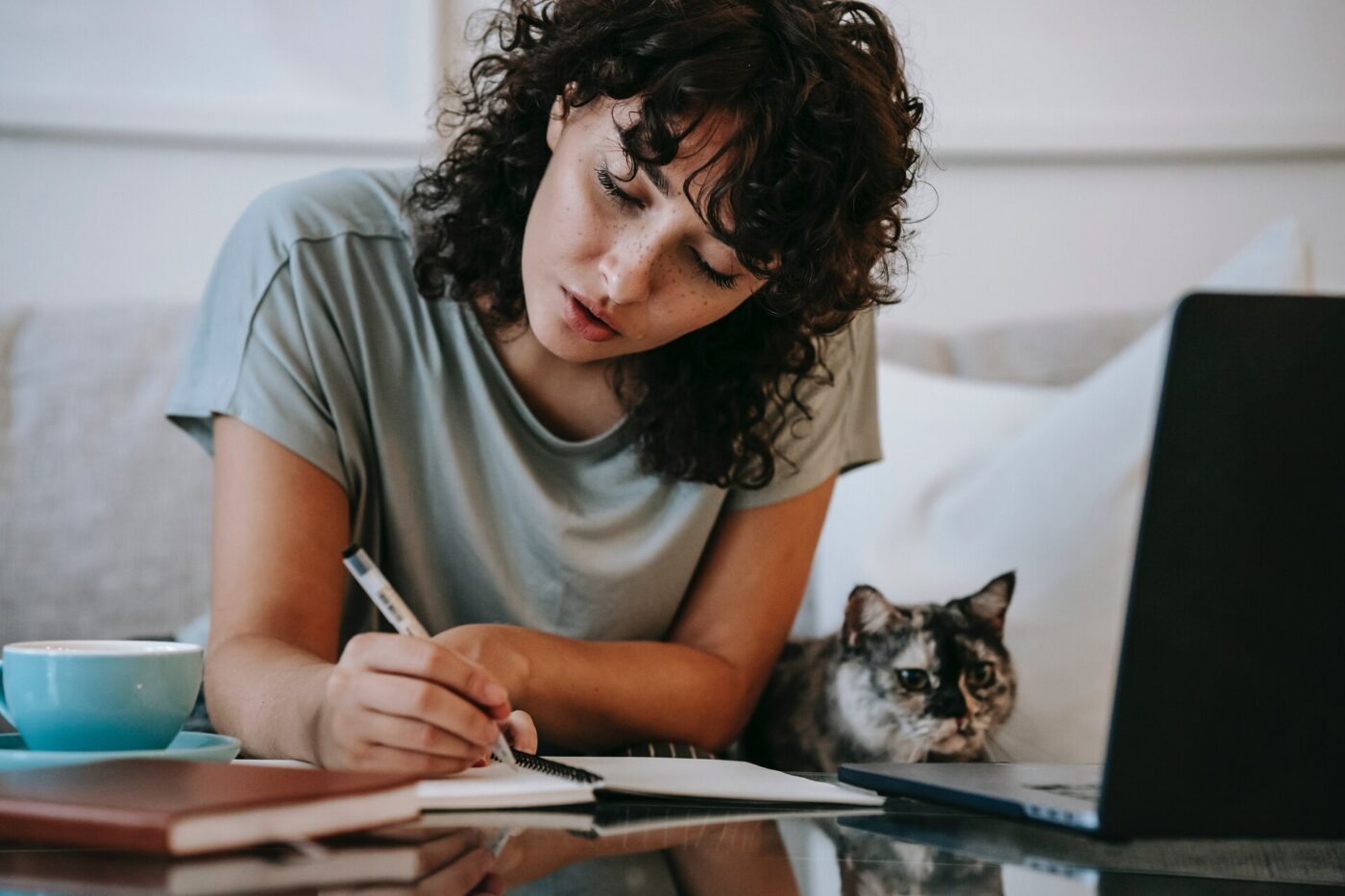 Woman making notes next to a cat