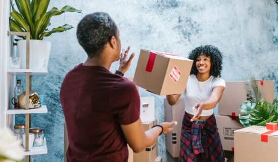 Two people tossing a cardboard box