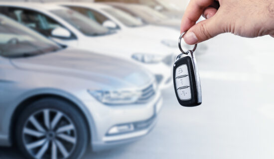 A man holding car keys in front of cars