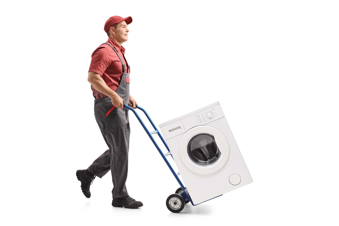 Full length profile shot of a mover pushing a hand truck loaded with a washing machine isolated on white background
