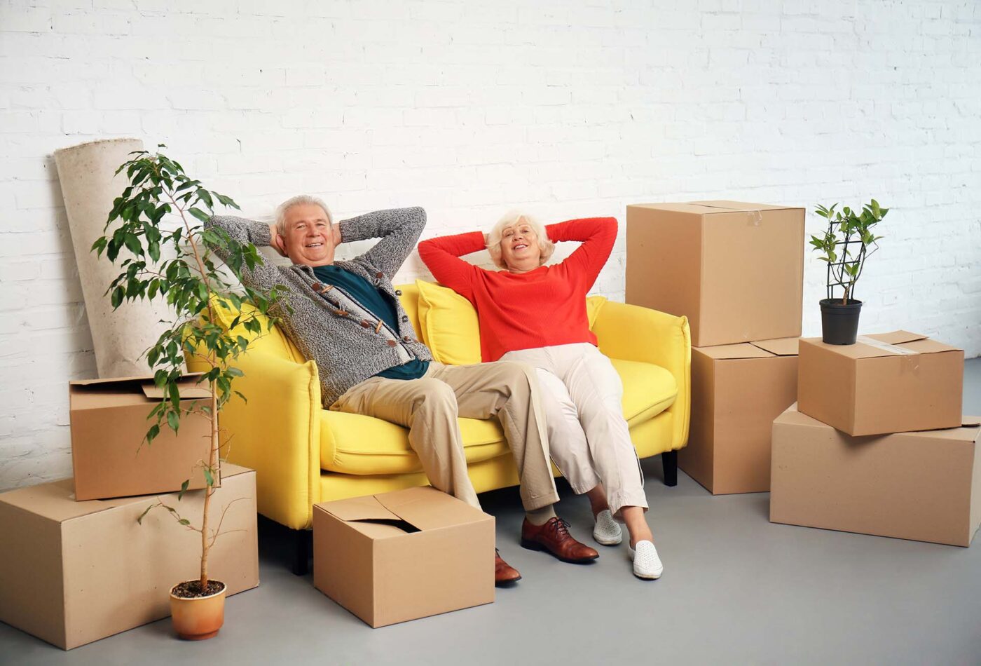 Mature couple sitting on sofa near boxes after moving into new house