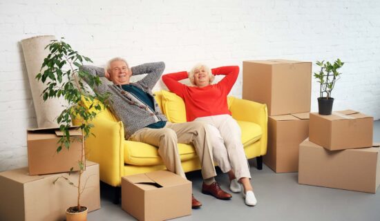 Mature couple sitting on sofa near boxes after moving into new house