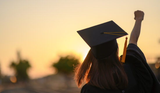 A girl with a graduation cap during the sunset