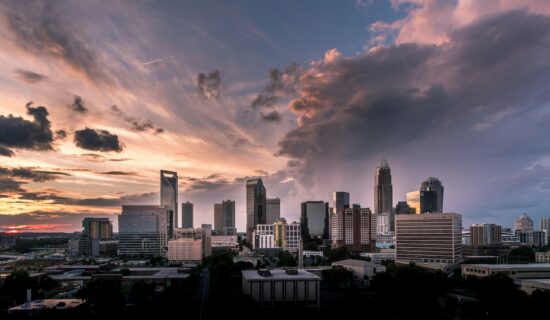 Bird's-eye view of downtown Charlotte city skyline at sunset with illuminated skyscrapers.